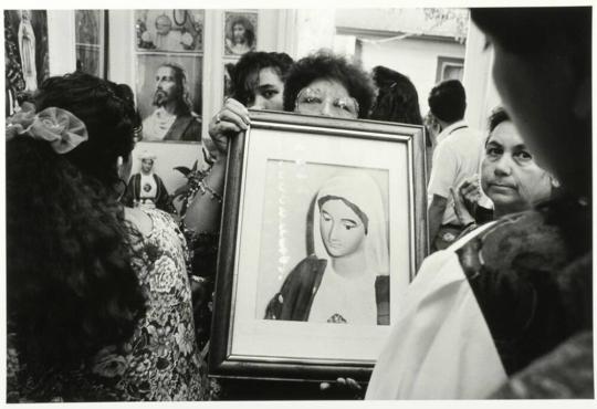 Woman Holds Picture of Weeping Virgin Mary Statue