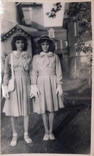 [two girls dressed in uniform in front of building]