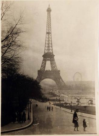 [view of the Eiffel Tower with populated street]