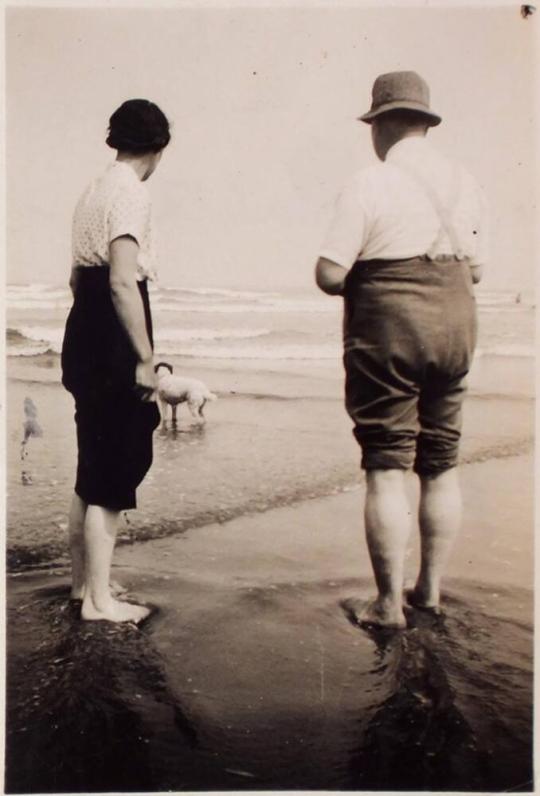 [backs of man and woman with pants rolled up standing on beach with dog "Mam & Dad / at Saltburn / Summer 1935"]