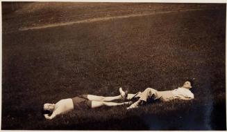 [two people laying on grass]