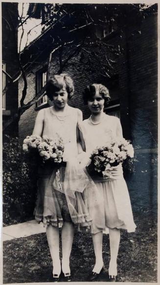 [two women dressed similarly with bouquets]