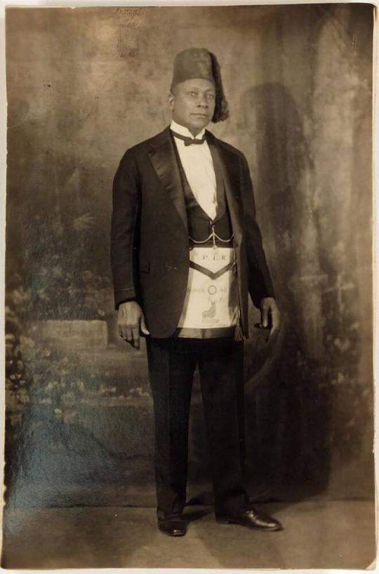 [postcard- man in tuxedo with men's club hat and apron]