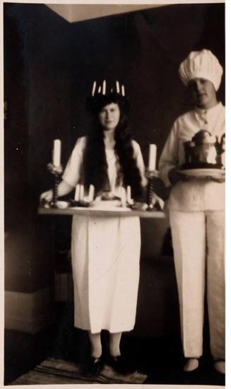 [woman wearing crown of candles and chef holding trays]