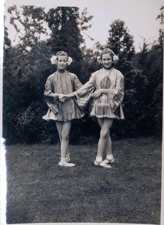 [two girls in costume in dance pose on lawn]