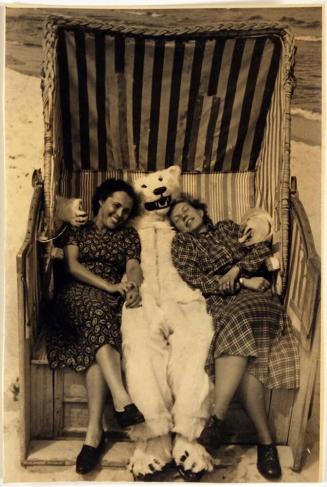 [two women sitting next to a figure in a bear costume]