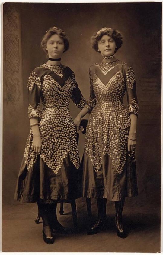[postcard- two women in the same dresses standing in front of chairs "Alma Johnson at right"]