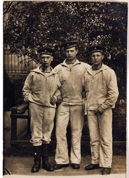 [three men in military iniform arm in arm]