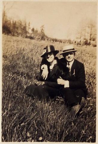 [man and woman in hats sitting on grass]