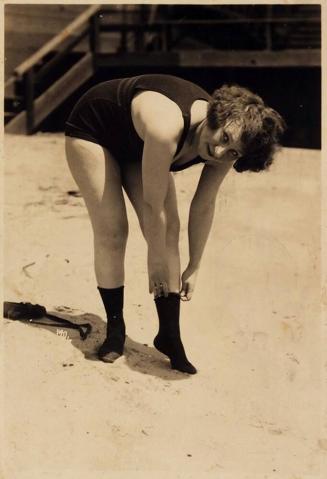 [Woman in Dark Swimsuit and Socks Bending over to Straighten Sock]