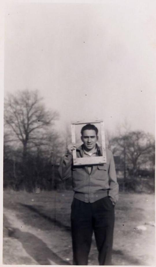 [man holding picture frame in front of face standing outdoors "April 1951 / Park."]