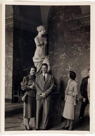 [man and woman posing in front of Venus de Milo with woman on right looking at sculpture]