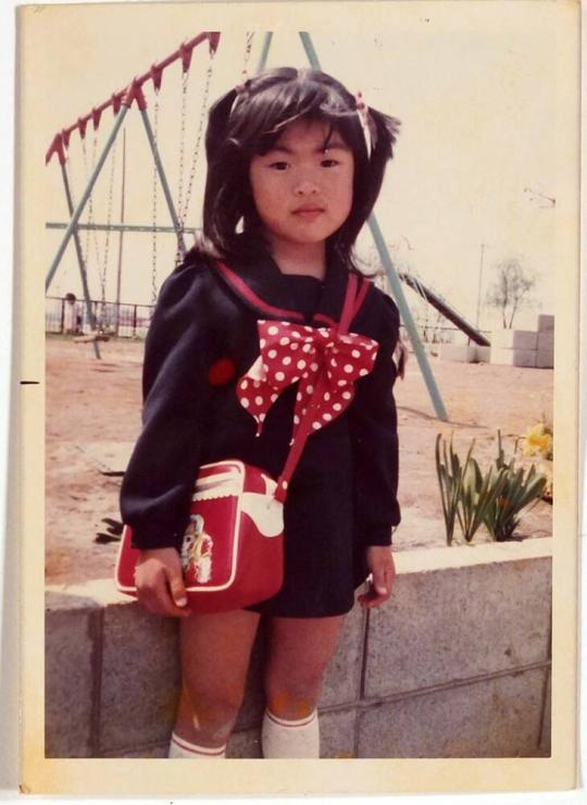 [girl wearing dark blue and red in front of playground]