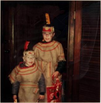 [two children dressed in costumes with plastic bag]