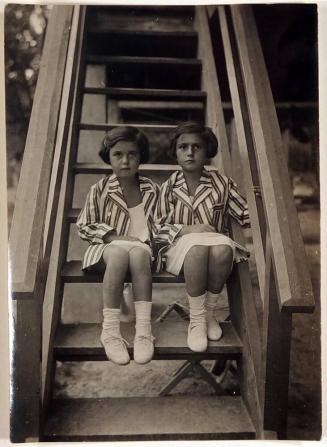 [two girls sitting on stairs dressed identically]