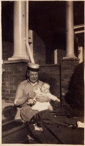 [man with brimless hat and baby sitting on steps]