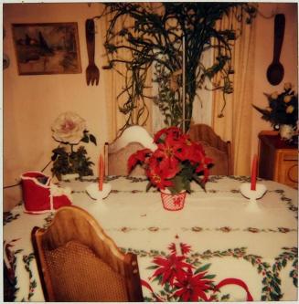 [table set with pointsetta and red, white, and green decorations]