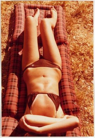[woman in bikini laying on plaid raft on grass]