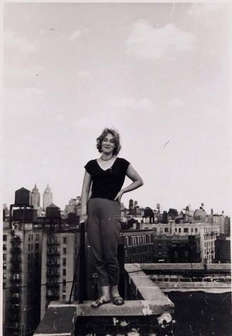 [woman standing on building with cityscape in background]
