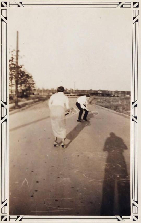 [man and woman with tennis rackets in street]