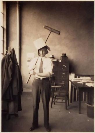 [man wearing box as a hat holding a push broom]