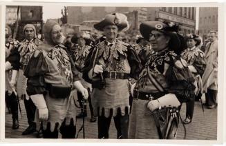 [men in costume with three in foreground]