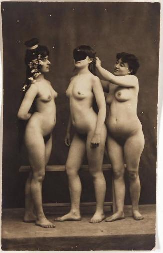 [three nudes, one putting mask on other]