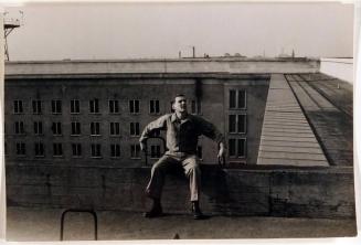 [man in uniform sitting on roof next to edge]