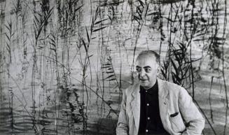 Portrait of Brassaï in front of his panel at UNESCO, 1957