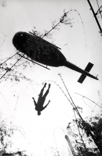 The body of an American paratrooper killed in action in the jungle near the Cambodian border is raised up to an evacuation helicopter, Vietnam