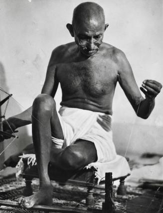 Gandhi using his spinning wheel at home