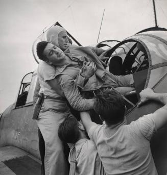 Wounded gunner Kenneth Bratton is lifted from the turret of a torpedo-bomber on his return to the USS Saratoga from a raid on Raboul