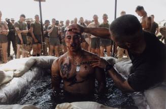 Navy Chaplain Lt. Commander Tom Webber baptizes Corporal Albert Martinez in a sandbag-lined pool during a ceremony at Camp Inchon, Kuwait