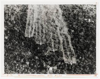 A flight of four U.S. Air Force Ranch Hand C-123s spray a Vietcong jungle position with a defoliating liquid