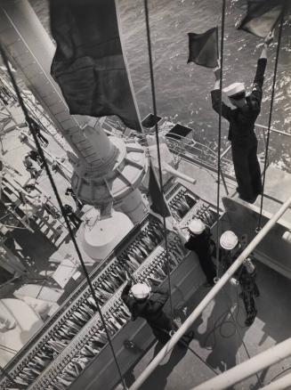 Navy Signalman using semaphore flags as he communicates with another ship while Signalmen handle the signal flag hoists on board the USS Maryland, San Pedro, CA
