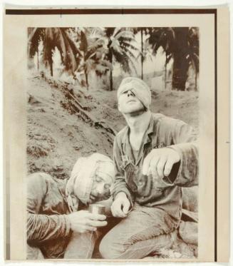 "Wearing a bloody bandage over the left side of his face, medic Thomas Cole of Richmond, Va., cradles the head of Staff Sergeant Harrison C. D. Pell from Hazelton, Pa., of the First Cavalry Division."