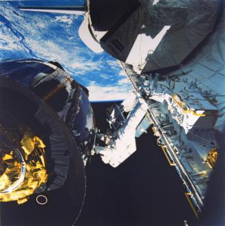 Mission: Space Shuttle 51-I, Discovery: Anchored to a foot restraint on Discovery's starboard side, William F. Fisher hangs onto the Syncom IV-3 communications satellite