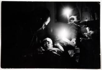 American soldiers tending wounded child in cellar of a house by candlelight
