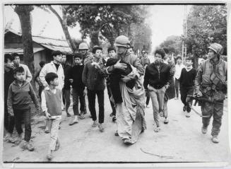 Wounded child caught in the cross-fire being taken from the front by Army medic, Hue