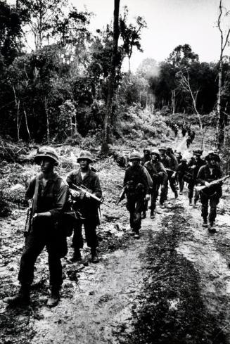 U.S. Airborne sweep through rain drenched forest at dusk trying to make contact with Vietcong