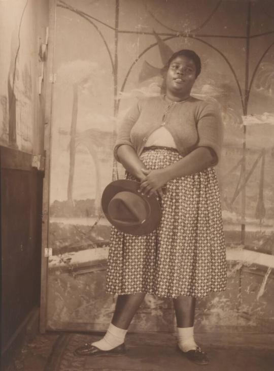 [Woman Holding Hat with Painted Backdrop]