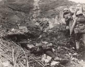 Passing a dead Jap [Japanese soldier] with hardly a glance the members of the 40-man combat patrol continue the difficult climb up the steep side of Mt. Suribachi.