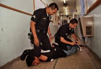 Officers at the Rampart Station restrain a man resisting arrest, LAPD