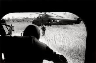 Disgorged from the helicopter, with covering fire from Farley, the troops run for a ditch between the paddies, Vietnam

