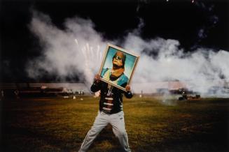 A Qaddafi supporter holds a portrait of the Libyan leader during a celebration staged for a group of visiting foreign journalists after regime forces re-took the city from rebels, Zawiyah, Libya