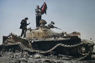 Libyan rebels celebrate on top of a Gaddafi loyalist tank outside of Ajdabiyah