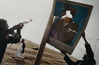 Opposition troops shoot at a portrait of Colonel Gaddafi as they celebrated taking Ben Jawad, Libya