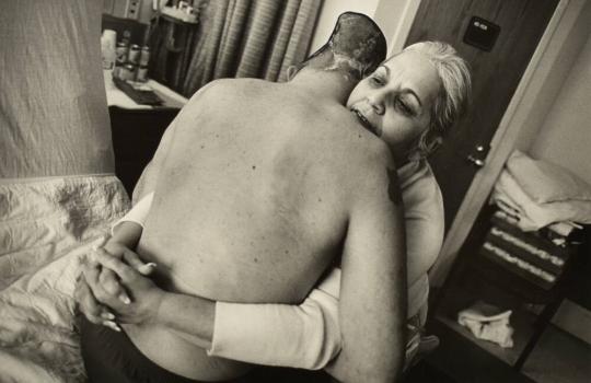 Nelida Bagley helps her son Sgt. Jose Pequeno from his bed at the West Roxbury Veterans Medical Center in Massachusetts