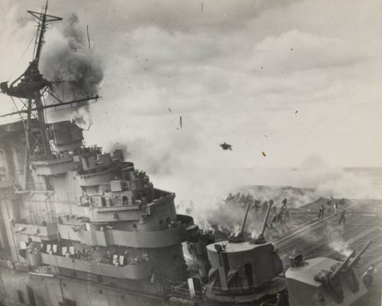 Picture taken at the instant of a high order detonation on port side. Note debris in air and firefighters running to escape. Note topmast broken at radar platform level.