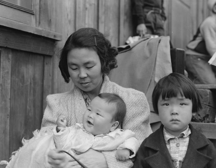 Centerville, California. Members of farm family await evacuation bus. In March they came from Santa Barbara County to Alameda County, so that all members of the family could be evacuated together. Evacuees of Japanese ancestry will be housed in War Relocation Authority centers for the duration.
